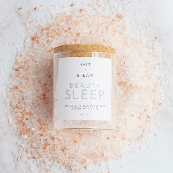 jar of bath salts laid on a pile of pink and white salt crystals