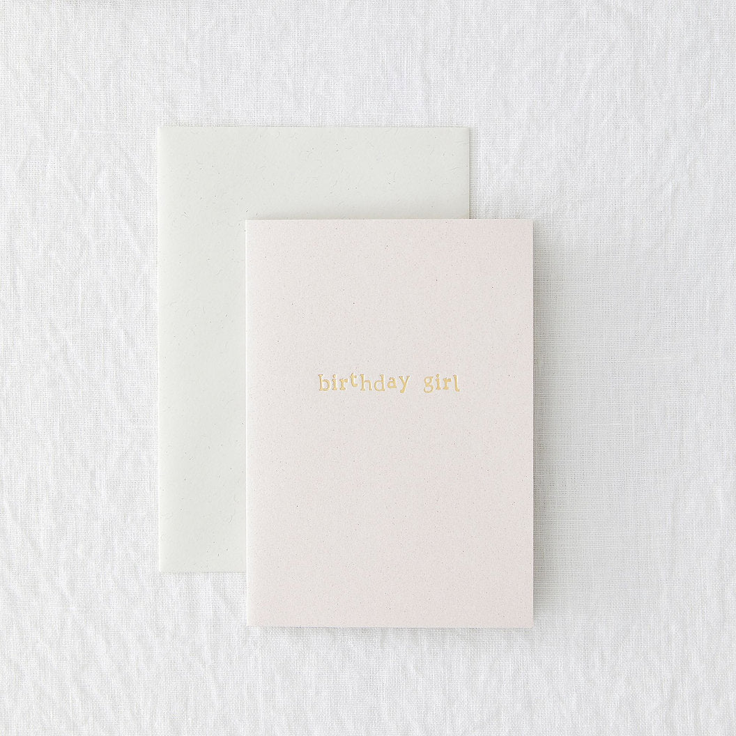 pink birthday card with gold foiled writing, laid on a grey envelope