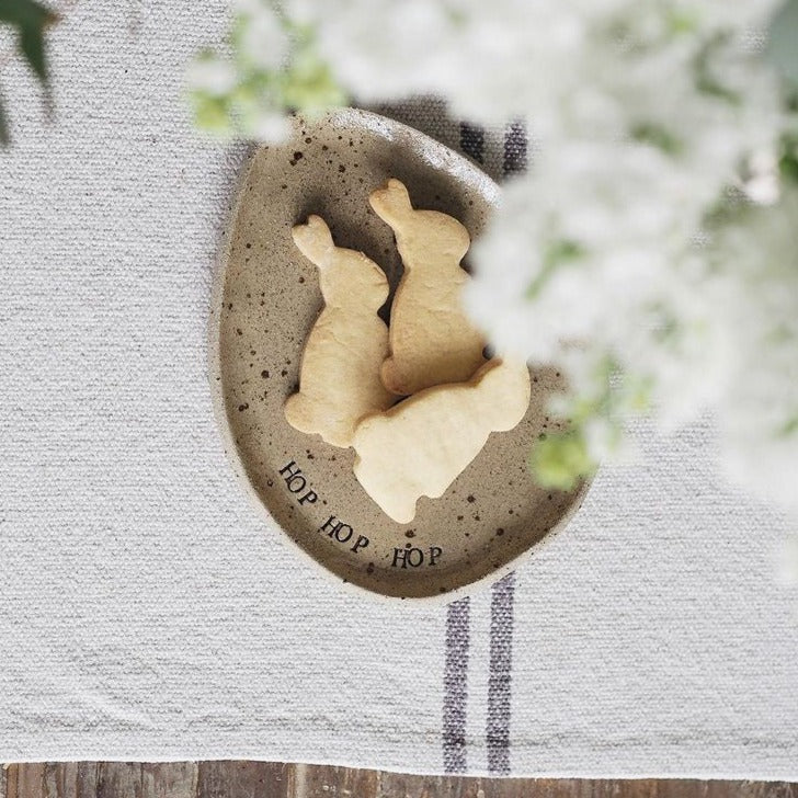 Shortbread bunnies laid on an egg shaped plate laid on a white linen tea towel