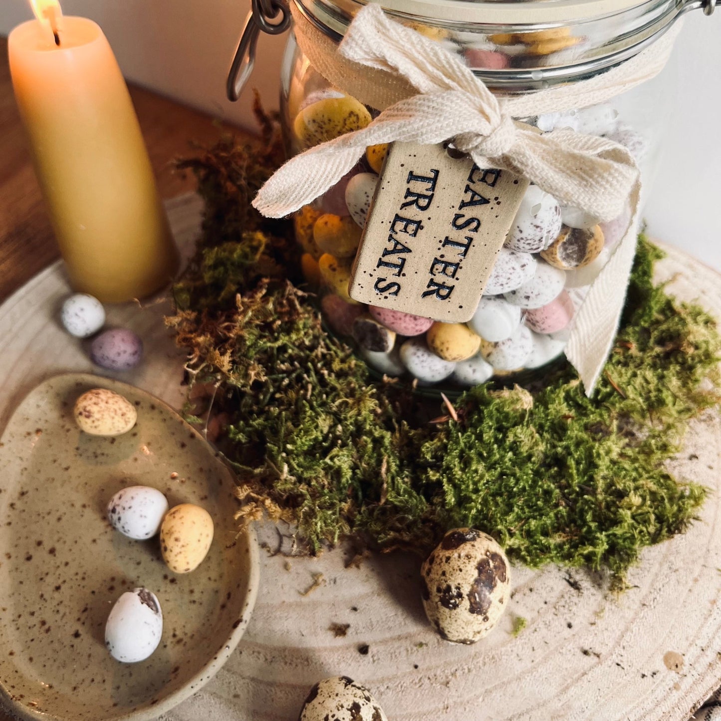 close up of ceramic tag tied around a glass jar filled with mini eggs