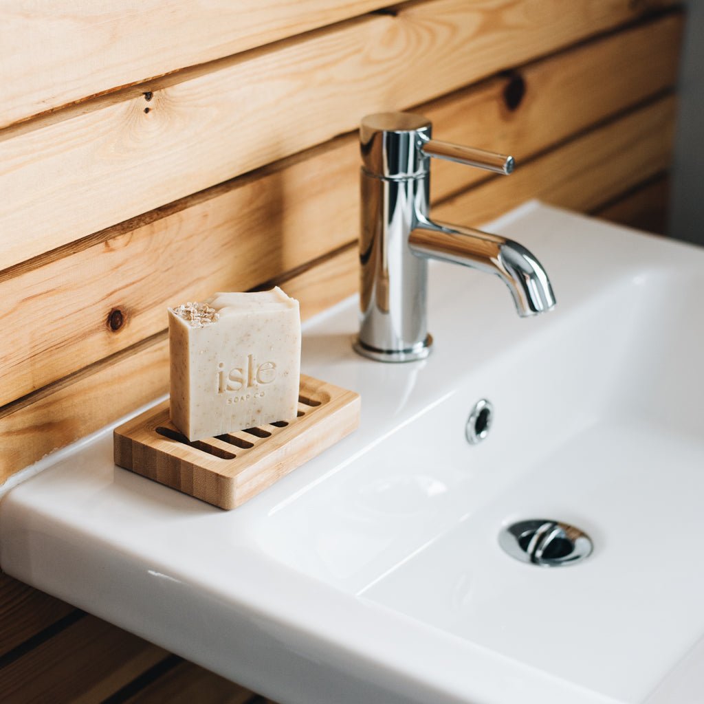 a cream bock of soap standing on a wooden soap dish on the sink