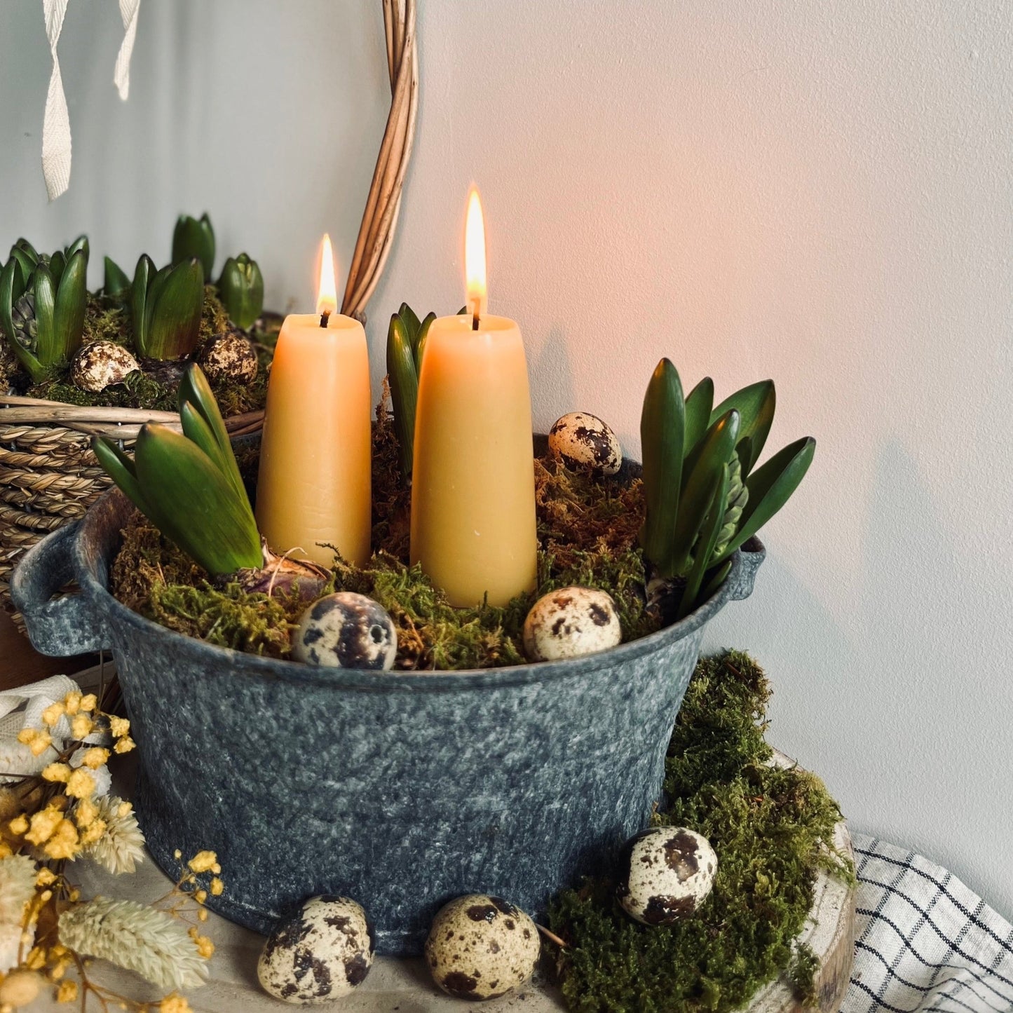 Pair of yellow candles, standing in a wrought iron pit on a bed of moss