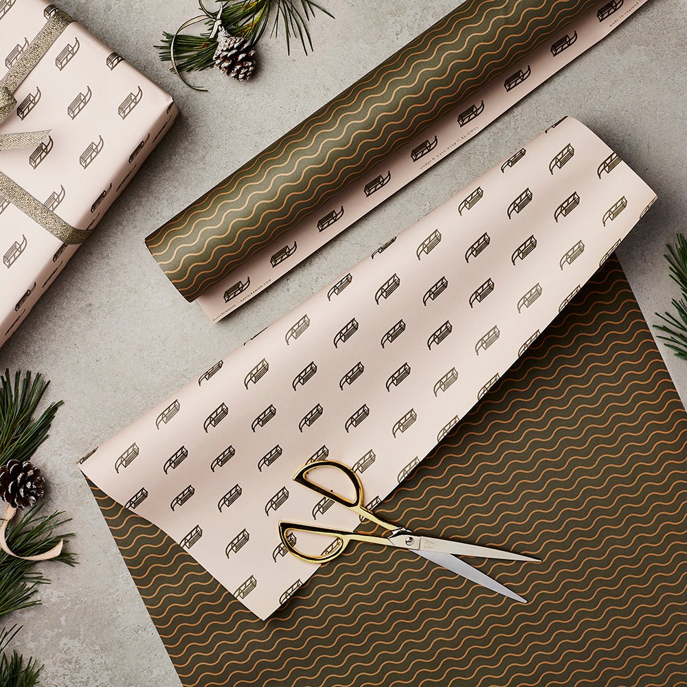 Wrapping paper flat lay showing the double sided designs. One side with gold sledge pattern, the other with a green and gold wavy design.