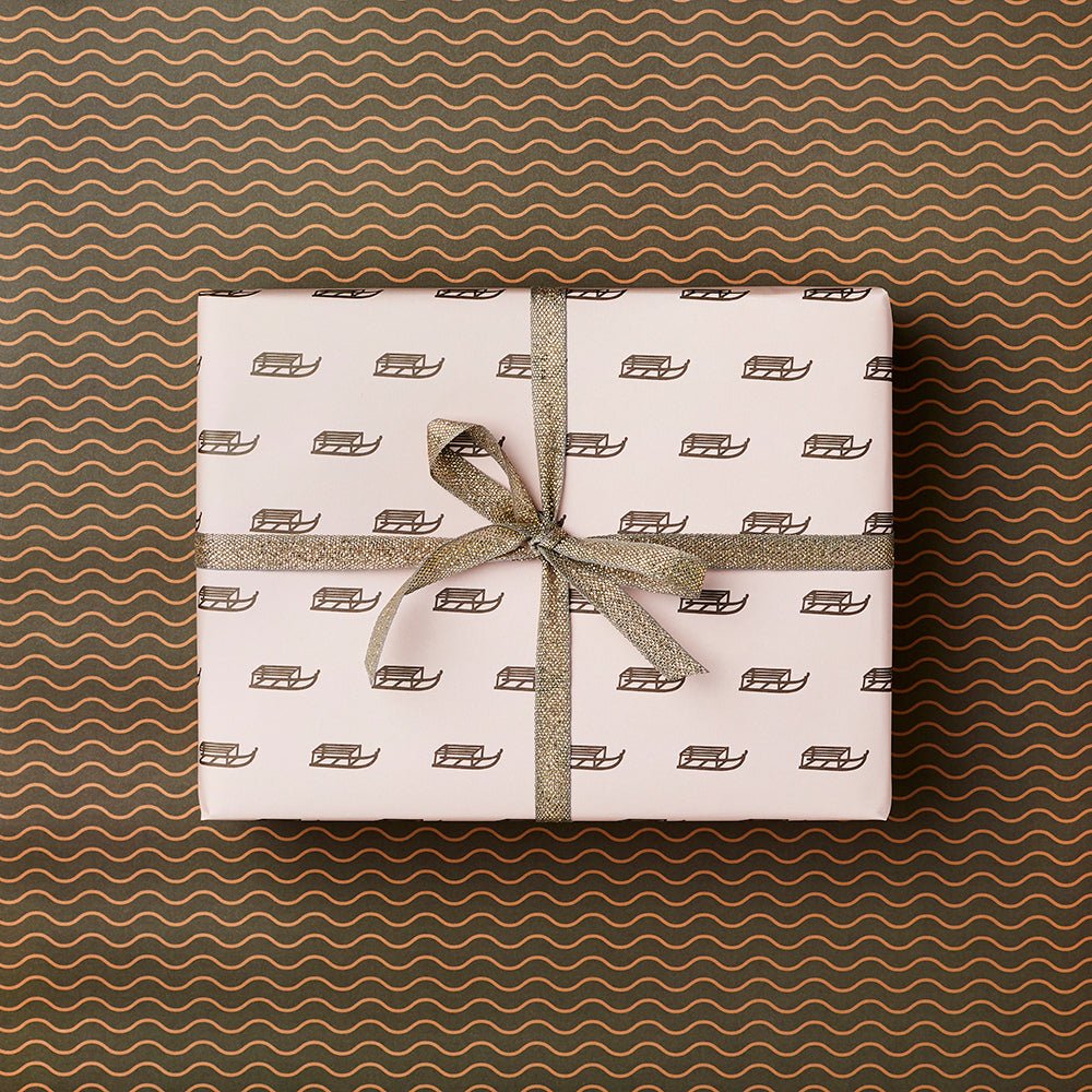 A present wrapped up in pink paper with gold vintage sledge design.