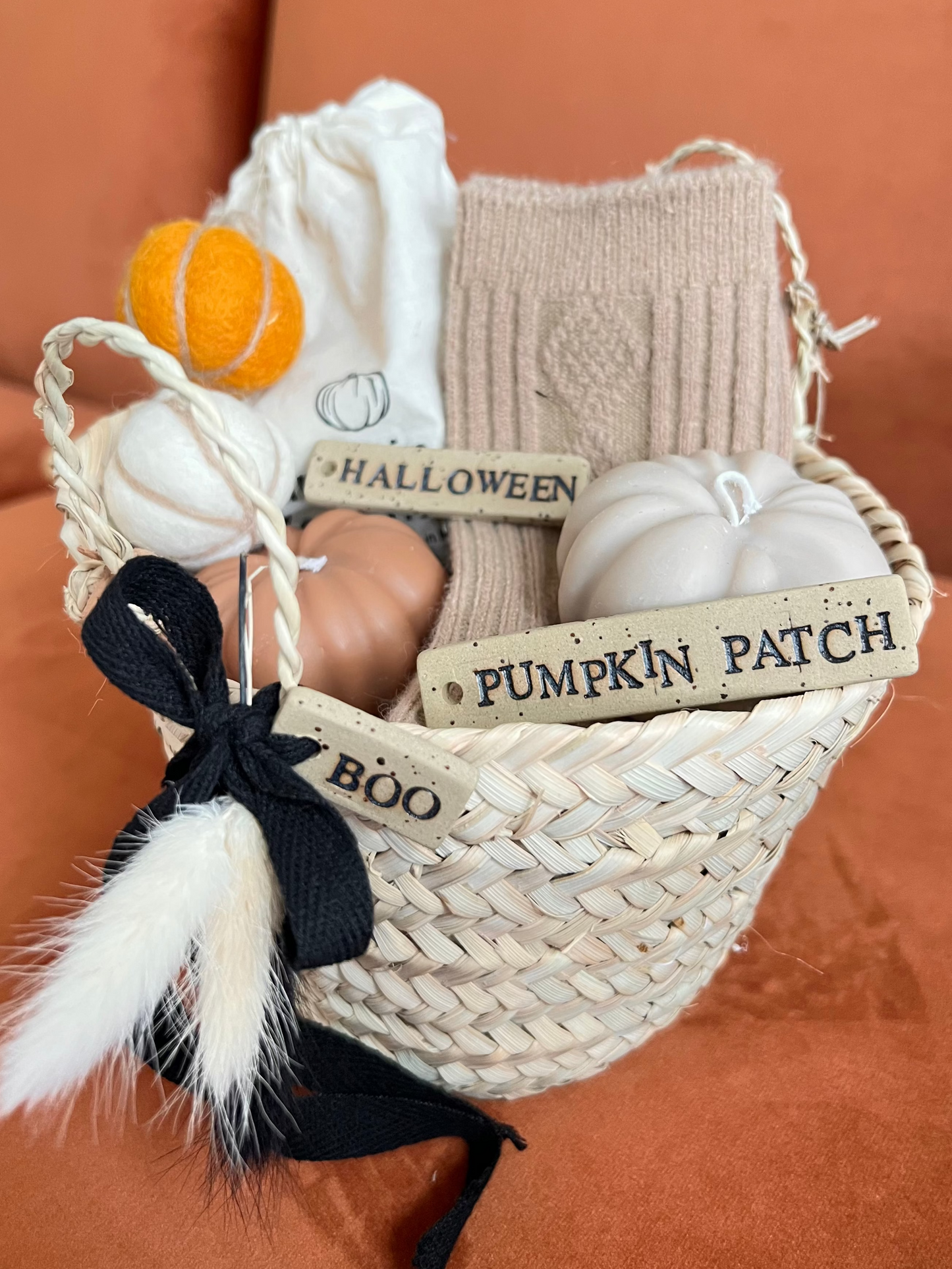 Decorative basket with Halloween-themed items including pumpkins, cosy socks and ceramic tags