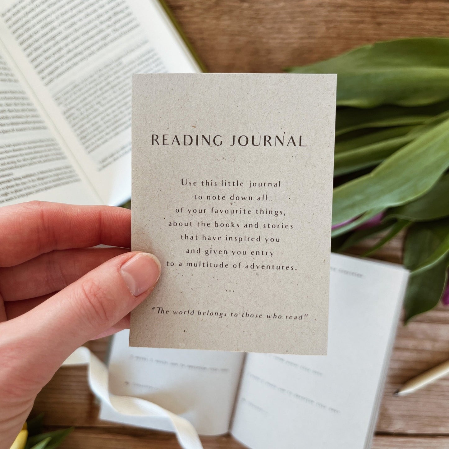hand holding a slip of paper, which explains what the reading journal is for