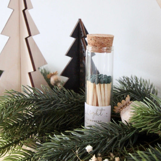 glass jar with cork lid holding green tipped matches.