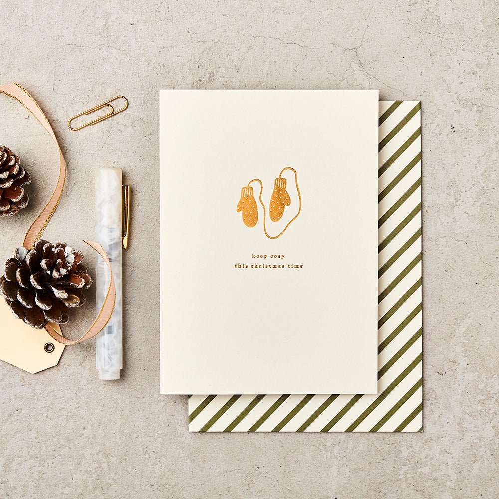 Christmas card with message 'Keep Cosy this Christmas time'. Featuring gold foiled mittens.