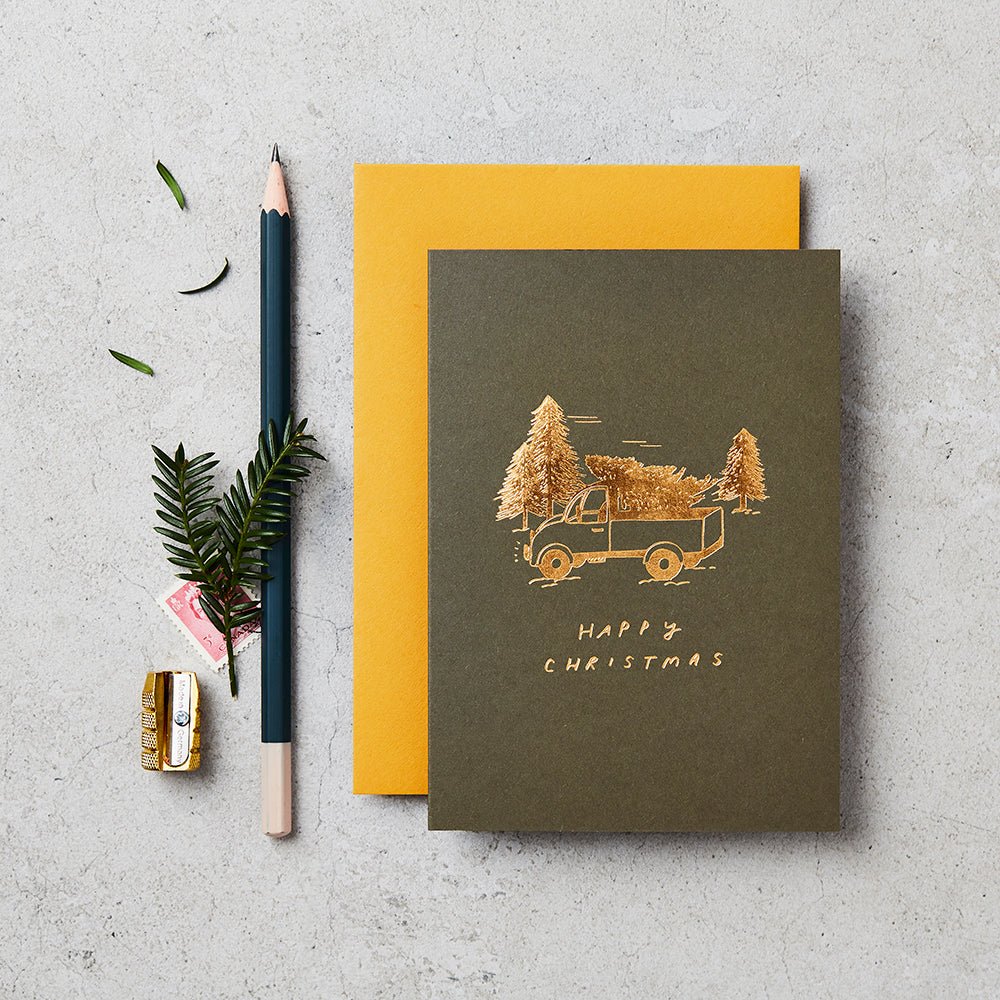Greetings card with gold foiled illustration of a truck and tree, with message 'Happy Christmas'