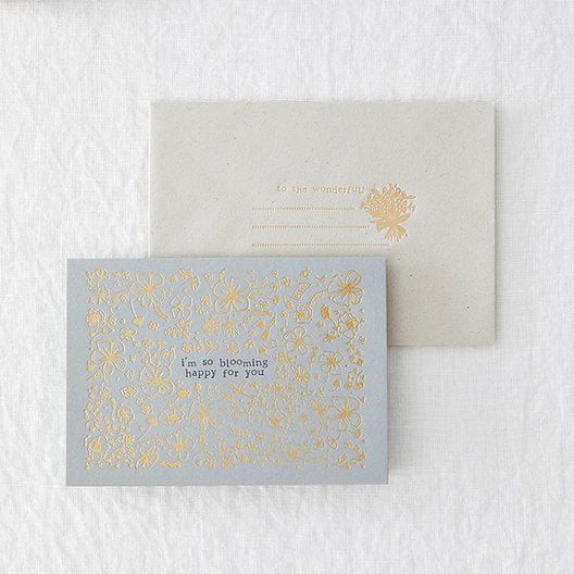 blue landscape greetings card with gold foiled floral design, laid on a grey envelope with gold foiling