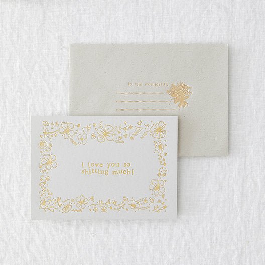 grey landscape greetings card with gold foiled floral design, laid on a grey envelope with gold foiling