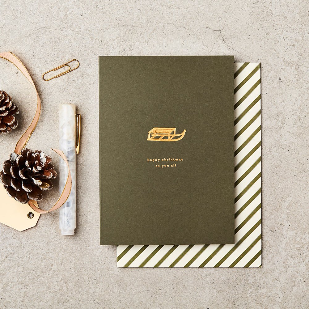 Green Christmas card with gold foiled message ' Happy Christmas to you all' and illustrated sledge